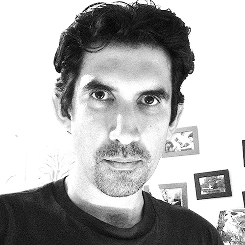 Headshot of man in black and white with dark hair, dark eyes and light skintone
