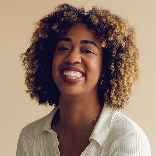 Headshot of woman with curly hair and medium dark brown skintone
