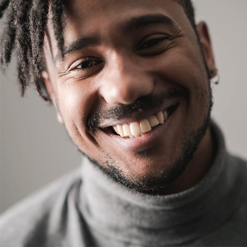 Headshot of man smiling with dark brown skin tone and natural dark hair