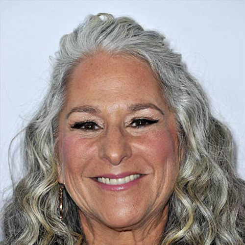 Headshot of woman with lots of wavy grey hair and dark eyes
