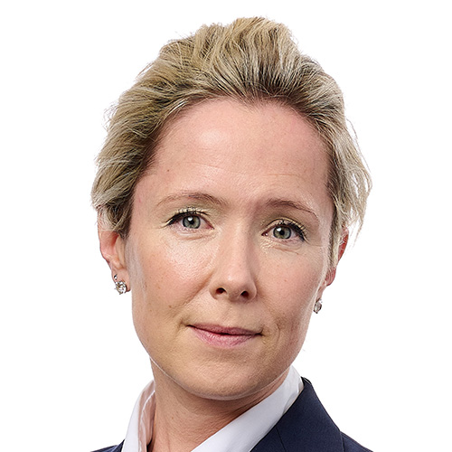Headshot of woman in a suit with blond hair pulled back and light skin tone
