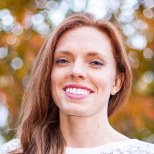 headshot of woman with light red hair, light skin tone smiling at the camera
