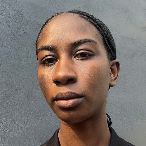 headshot of woman with dark down hair in braids with dark brown skin tone and dark brown eyes