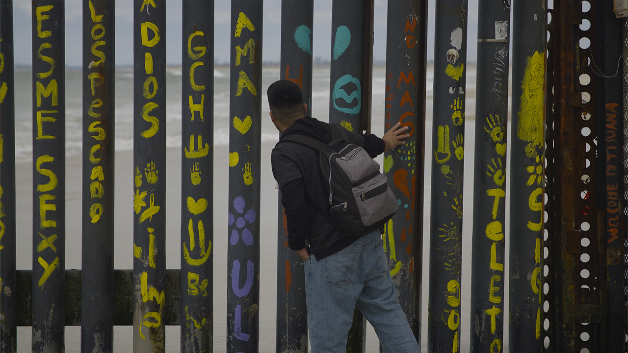 Man looking through boarder fence