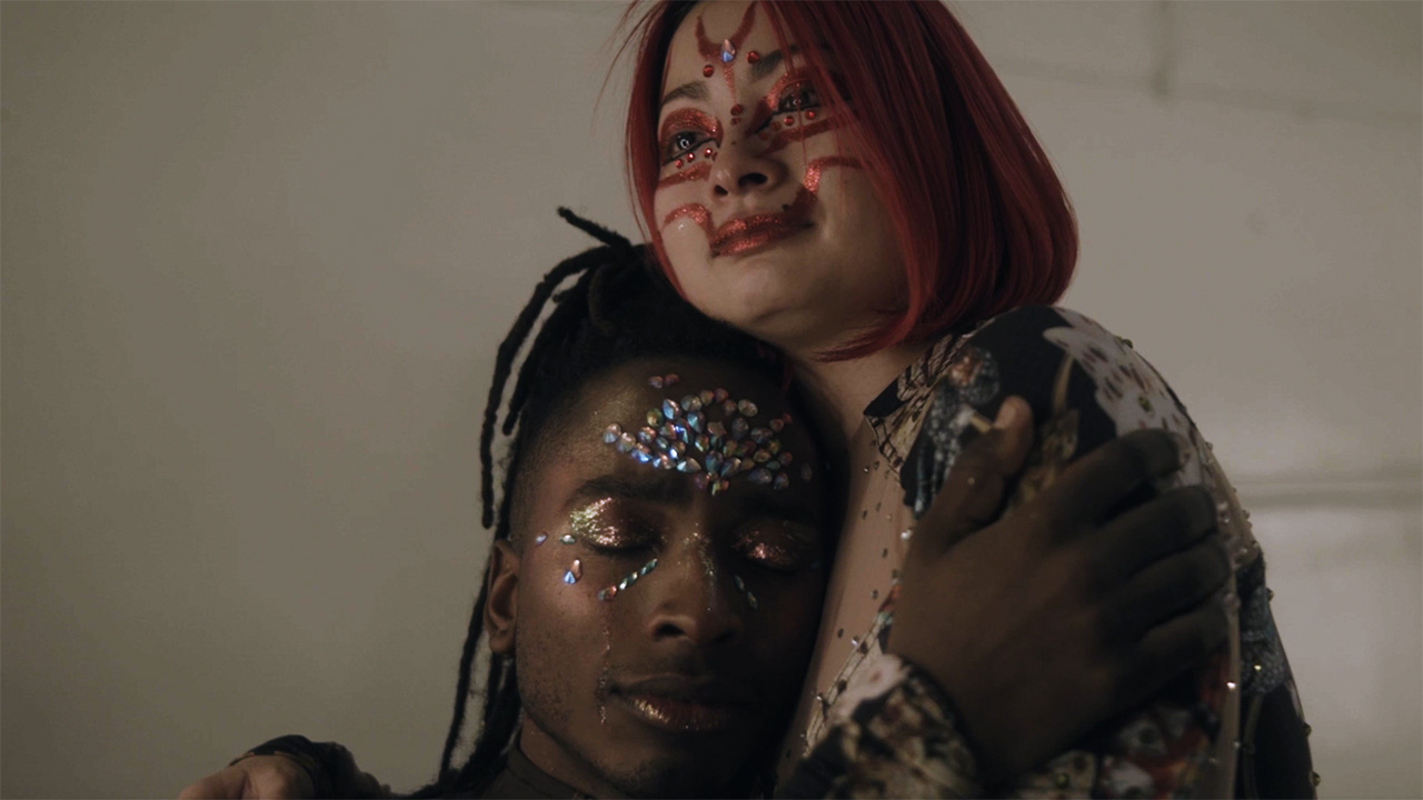 person wearing stick on jewles on face being embraced by someone else with face painting