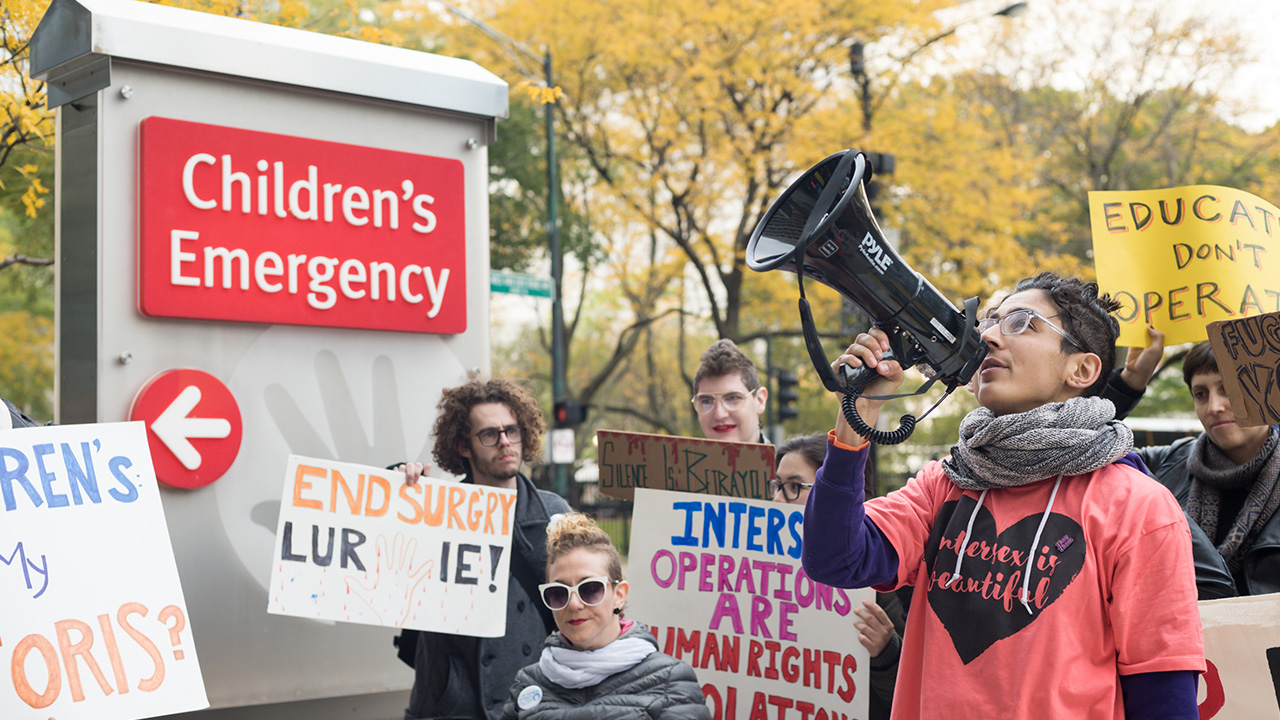 Person holding megaphone in a crowd of people holding protest signs