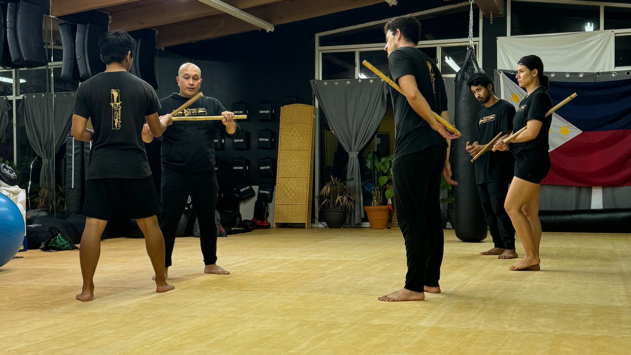 Group of people in a fitness studio holding wooden sticks