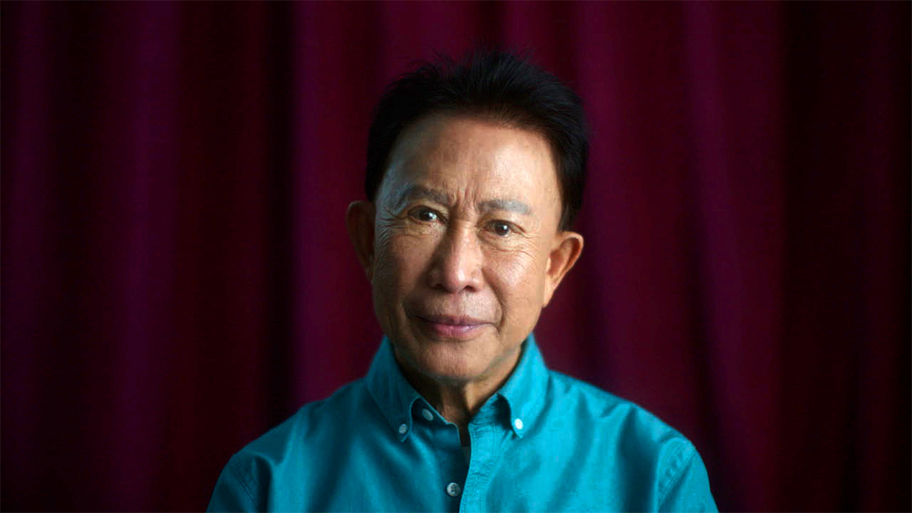 A older asian man looking directly into the camera 