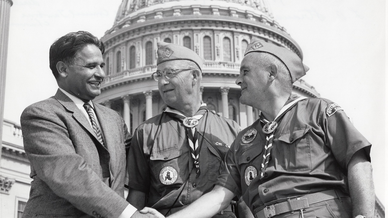 three men two in military uniforms shaking hands