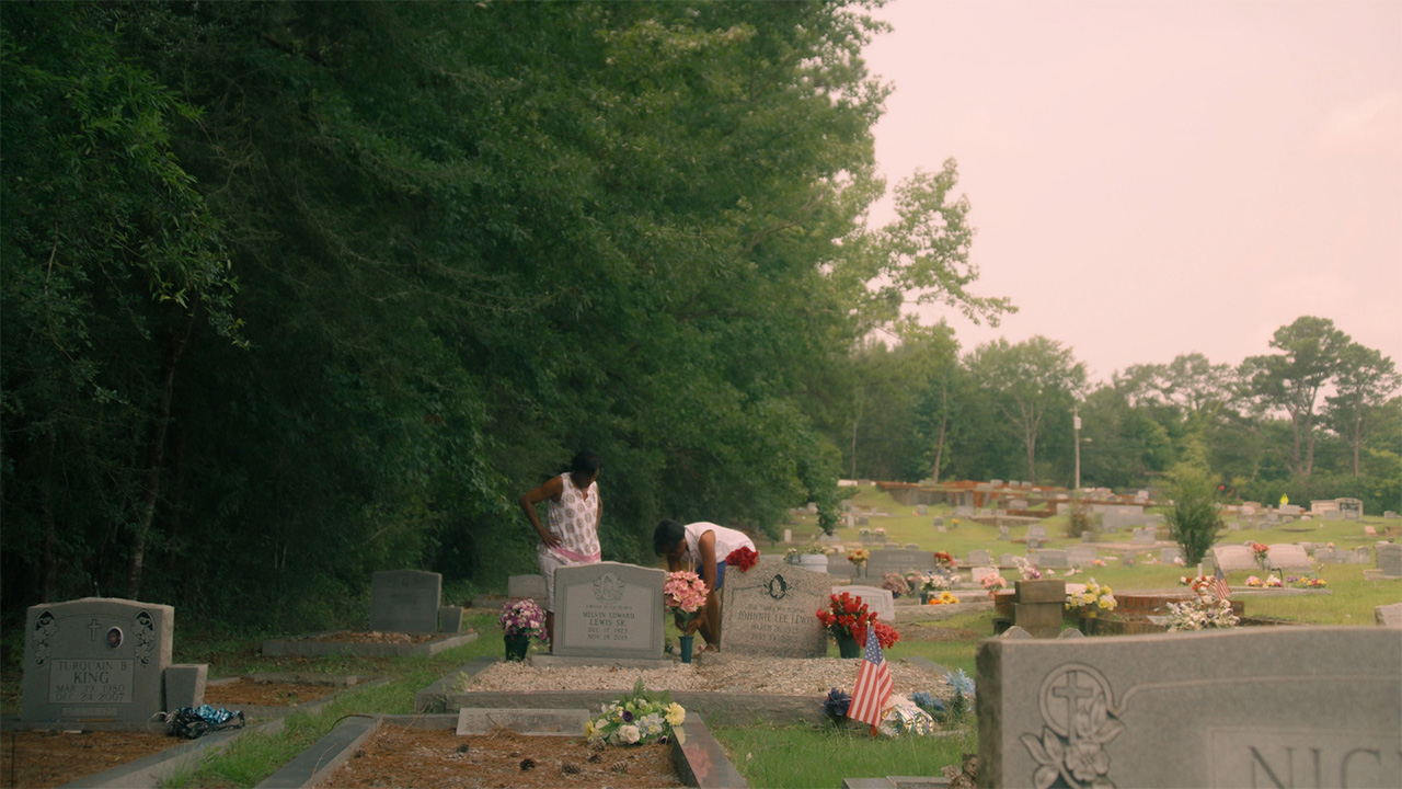 a couple people in a grave yard laying flowers at a grave