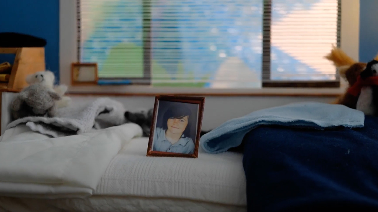 Photo of young person sitting in a frame on an empty bed giving the sense of loss