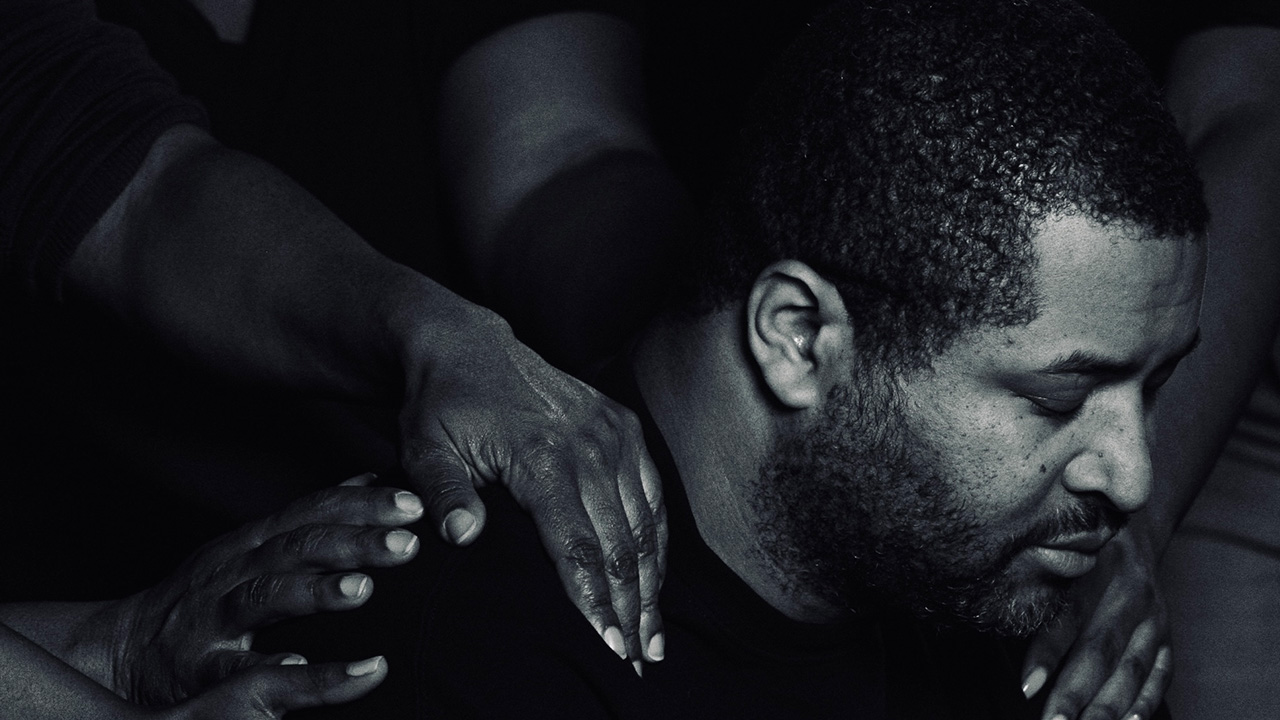 Man with head down and hands on his shoulders. A somber mood